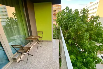 a balcony with two chairs and a green wall at Modern Apartment with Parking next to Bulgaria Mall in Sofia