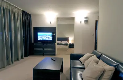 a living room with a couch and a television at Vitoshko Lale Hotel in Sofia
