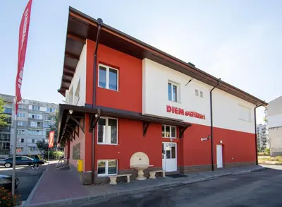 a red and white building on the side of a street at Apartments DIEM in Samokov