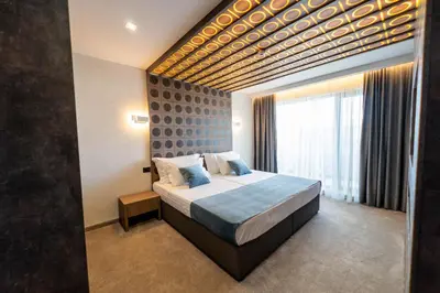 a bedroom with a large bed and a large window at 103 Degrees Hotel & Spa in Sapareva Banya