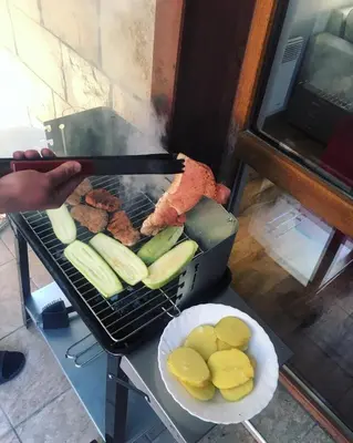 a person cooking meat and vegetables on a grill at Snow Apartment - Bansko in Bansko