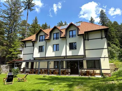 a large white building with tables and chairs in the yard at Berghof Eva - Hotel in Panichishte