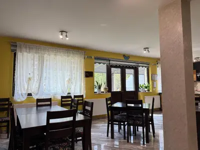 a dining room with a table and chairs and windows at Berghof Eva - Hotel in Panichishte
