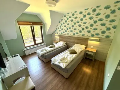 a room with two beds and a wall with two windows at Berghof Eva - Hotel in Panichishte