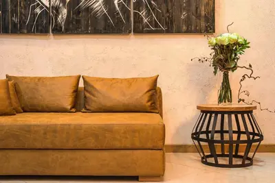 a brown couch with a vase of flowers on a table at THE STAY Boutique Hotel Central Square - Free Compliments - Free Wi-Fi - TOP LOCATION - Nearby Paid Parking in Plovdiv
