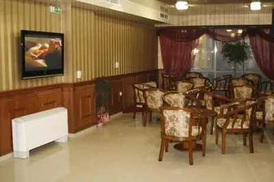 a room with a bunch of chairs and a tv at Hotel Elegance in Asenovgrad