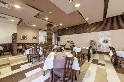 a dining room with white tables and chairs at Hotel Arena in Samokov