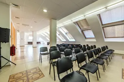 a room with rows of chairs in a room with windows at Hotel Arena in Samokov