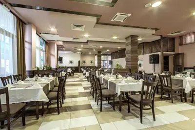 a dining room with white tables and chairs at Hotel Arena in Samokov