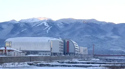 a large white building with mountains in the background at Hotel Arena in Samokov