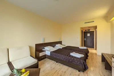 a hotel room with two beds and a chair at Hotel Arena in Samokov