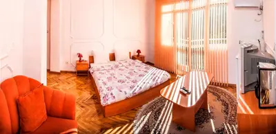 a bedroom with a bed and a chair and a tv at Central GuestHouse Five Corners in Sofia
