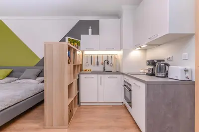 a kitchen with white cabinets and a bed in a room at The Spot - fully equipped, central, modern studio by Flat Mаnager in Sofia