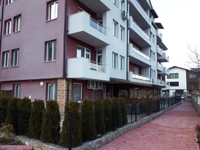 a pink building with a fence next to a brick sidewalk at ApartVel apartment 2 in Velingrad