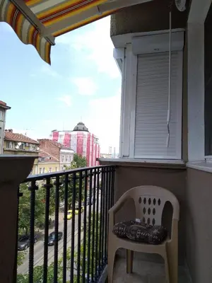a chair on a balcony with a view of a street at Maria Louisa Apartment in Sofia