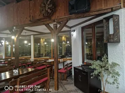 a restaurant with wooden tables and benches and a clock at Ribkata Family Hotel in Smolyan