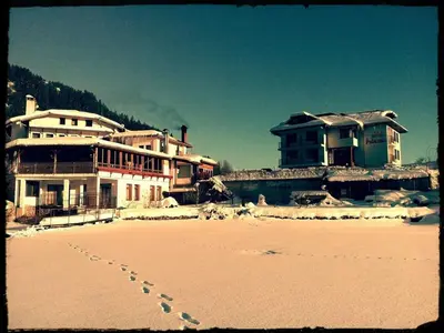 a group of buildings on a beach with footprints in the sand at Ribkata Family Hotel in Smolyan