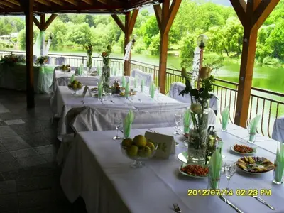 a table with white table cloths and vases with fruit on it at Ribkata Family Hotel in Smolyan