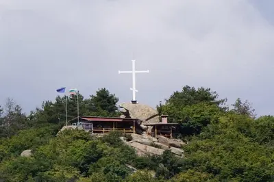 a cross on top of a hill with a church at Апартамент 13 in Hisarya