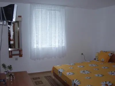 a bedroom with a yellow bed and a window at Стаи за гости 