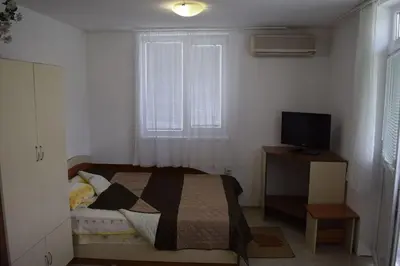 a bedroom with a bed and a desk with a television at Стаи за гости 