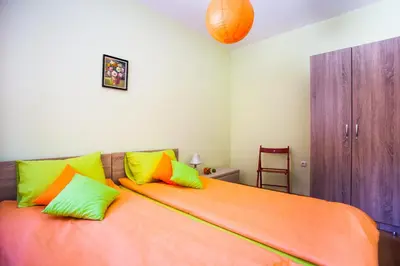 a bedroom with an orange bed with colorful pillows at Green Orange Apartment in Bansko