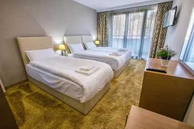 a hotel room with two beds and a window at Hotel Andon Angelov in Sandanski
