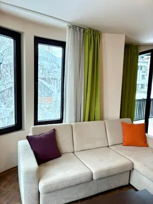 a living room with a couch and two windows at House Laudis in Bansko