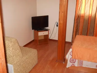 a room with a bed and a tv and a chair at Hotel Orient in Blagoevgrad