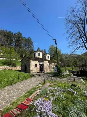 an old stone building in a field with flowers at Семеен Хотел Вит in Teteven