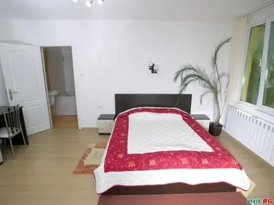 a bedroom with a large bed with a red and white blanket at ХОТЕЛ НИК in Asenovgrad