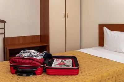 a red suitcase sitting on top of a bed at Primavera 2 Hotel in Pazardzhik