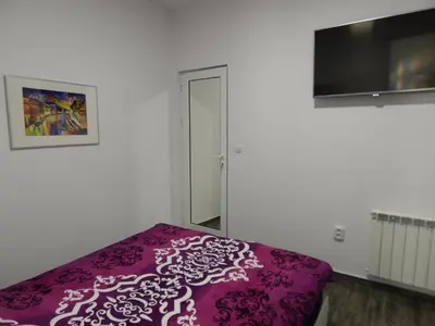 a bedroom with a purple bed and a flat screen tv at Red House in Kyustendil