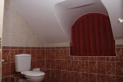 a bathroom with a toilet and a red curtain at Guest House Stelia in Velingrad