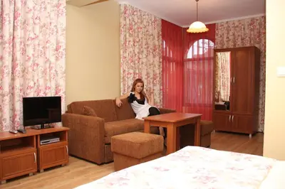 a woman sitting on a couch in a living room at Guest House Stelia in Velingrad