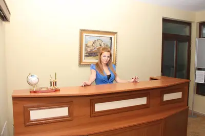 a woman sitting at a desk in a room at Guest House Stelia in Velingrad
