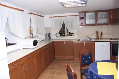 a kitchen with wooden cabinets and a white microwave at Guest House Stelia in Velingrad