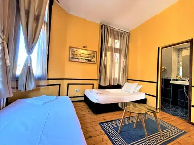 a room with two beds and a chair in it at L'Opera Guest House in Sofia