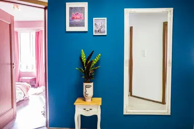 a blue wall with a vase on a table and a mirror at Baba Taki Apartment in Plovdiv