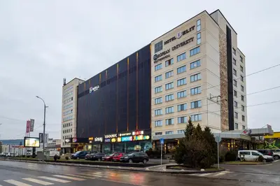 a large building with cars parked in front of a street at Hotel Elit in Pernik