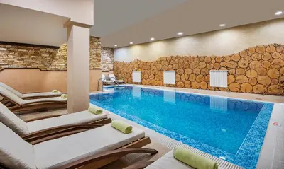 a pool in a hotel room with lounge chairs and a swimming pool at Apartments Bansko in Bansko