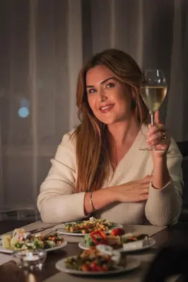 a woman sitting at a table with a glass of wine at Apartments Bansko in Bansko