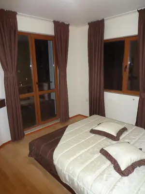 a bedroom with a large bed and windows at Ski & Holiday Apartments in Pamporovo in Pamporovo