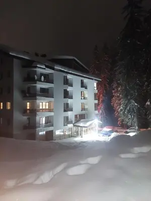 a apartment building in the snow at night at Ski & Holiday Apartments in Pamporovo in Pamporovo