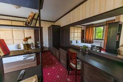 a room with two beds and a desk and a room with a desk at Hotel Villa Ofir in Sandanski