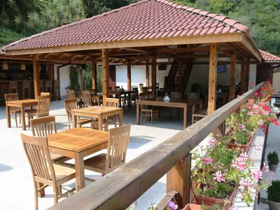 a wooden pavilion with wooden tables and chairs at Хотел Аква Варвара in Varvara