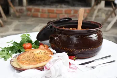 a table with a pot of soup and a plate of food at Djudjeva Kyshta Hotel in Panagyurishte
