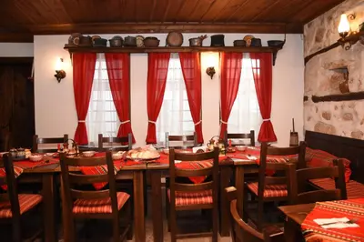 a dining room with a long table and red curtains at Djudjeva Kyshta Hotel in Panagyurishte