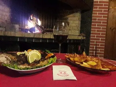 a table with a plate of food and a glass of wine at Семеен хотел НАЦИОНАЛ in Mineralni Bani