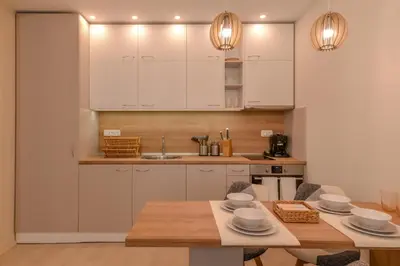 a kitchen with white cabinets and a wooden table at Sofia Dream Apartment - Premium One Bedroom on Ekzarh Yosif by Flat Mаnager in Sofia